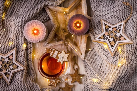 Cosy home and hygge concept - cup of tea with Christmas cookies, warm blanket and candles