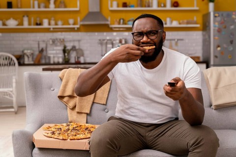 Man watching tv eating pizza