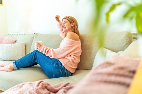 Horizontal photo full length and copy space of a blonde casual adult woman celebrating raising fist