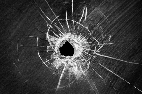 Bullet shot cracked hole on car windshield or accident damaged broken house window glass