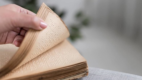 Close up hand holding old braille book