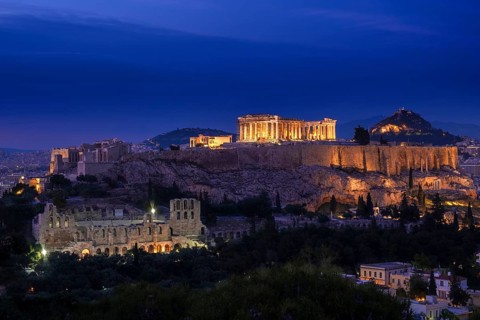 Iconic view of Acropolis hill in Athens, Greece at night. Delicate lights of Parthenon and Odeon