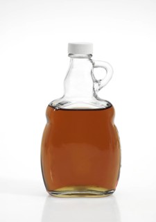 BOTTLE OF MAPLE SYRUP AGAINST WHITE BACKGROUND