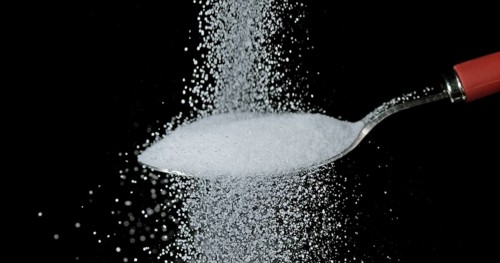 White Sugar falling against Black Background