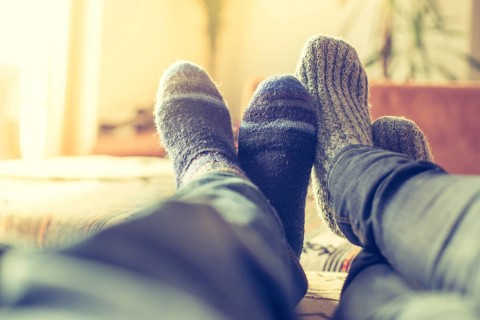 Feet with woollen socks in the wintertime: Couple is relaxing on the couch