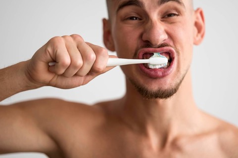 Front view man brushing his teeth morning