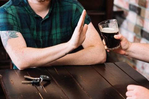 Man refusing glass rum offered by his friend