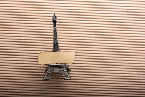 Burnt piece of paper on model Eiffel tower on cardboard