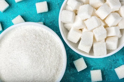White sugar in bowls on blue textured background