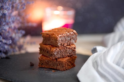 Homemade dark chocolate fudge brownies cake stacked on stone plate with copy space. Lavender