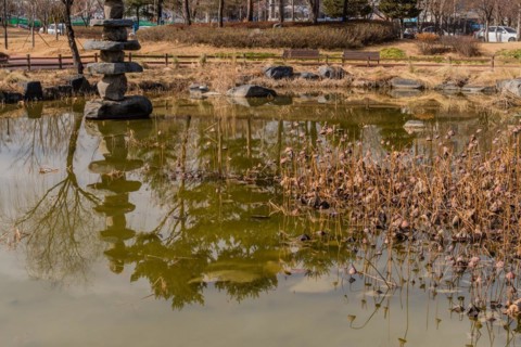 Stone tower in small pond in city park on sunny winter day in South Korea