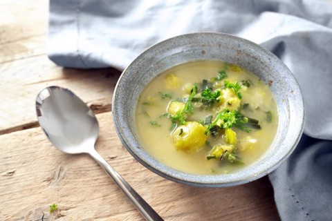 Vegetarian soup from vegetables like brussels sprout, leek and potato with parsley garnish in a