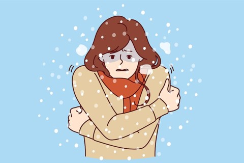 Woman freezes standing under snow in cold winter weather, dressed in sweater and needs warm down