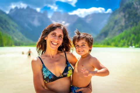 Mother and son smiling and enjoying summer vacation while swimming in the scenic lago di landro in
