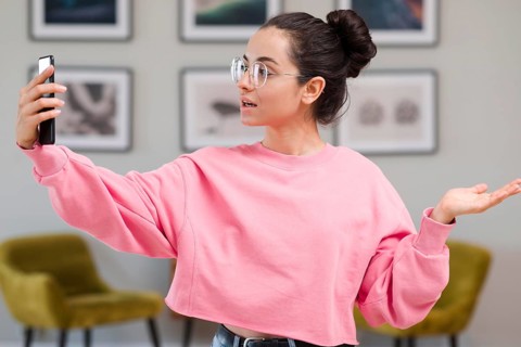 Blogger with glasses recording herself with phone