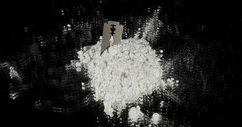 Powder Drug Falling on Razor Blade and Syringes against Black Background