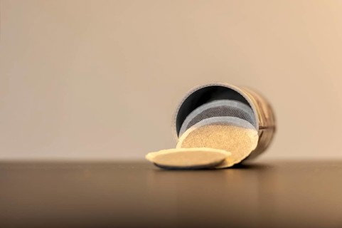 Coffee pods slide out of an open tin onto the table