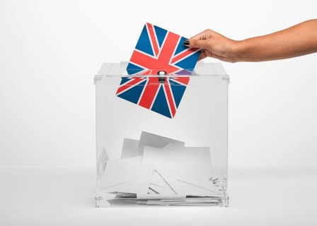 Person putting united kingdom flag card into ballot box