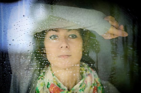 Young woman looks through the window in rainy weather