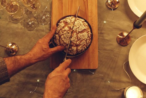 View from above of man cutting delicious freshly baked homemade pie cake with knife on rustic table
