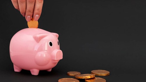 Person putting pink piggy bank coins