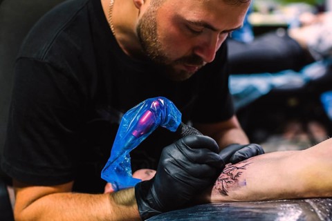 Master doing tattoo with iron salon