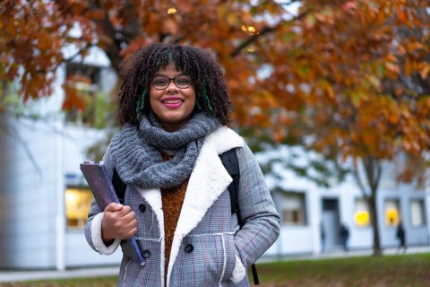 Portrait of black ethnic girl strolling in college college in fall back to school