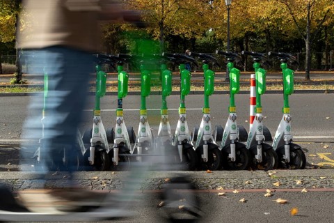 Traffic, mobility, motion blur, scooter riders and lined-up e-scooters from the provider Lime in