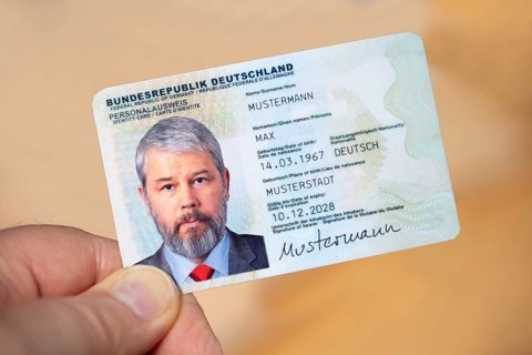 Hand holding an identity card of the Federal Republic of Germany with a businessman around 50 years
