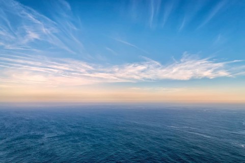 Beautiful seascape with calm sea or ocean waves. Atmospheric haze, colorful low clouds lit by