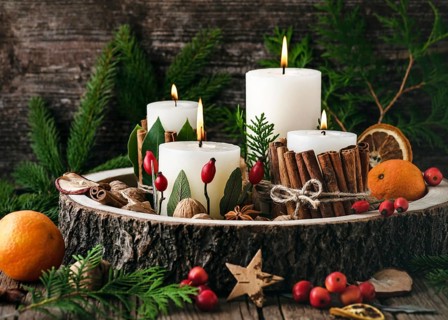 Advent wreath with four white burning candles decorated with natural materials. Slices of freshly