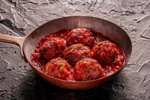 Meatballs. Beef meat balls in a pan, with parsley and tomato sauce, on a black slate background,