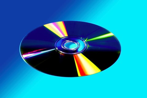 CD DVD disk with colorful reflexion over vivid blue background