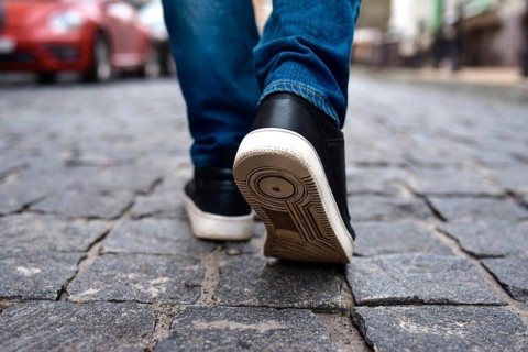 Legs view of a male walking on the road in the city. close up of black male shoes