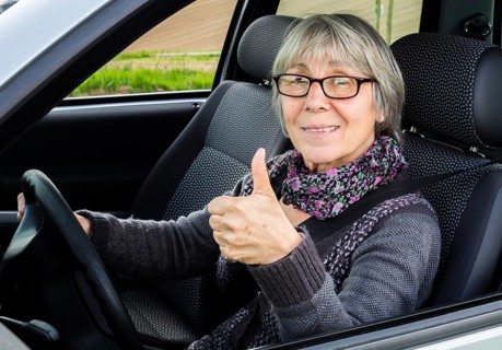 Senior citizen in car gives thumbs up