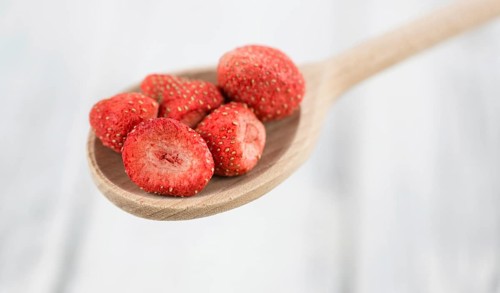 Strawberries (dried) as high detailed close-up shot on a vintage wooden table, selective focus