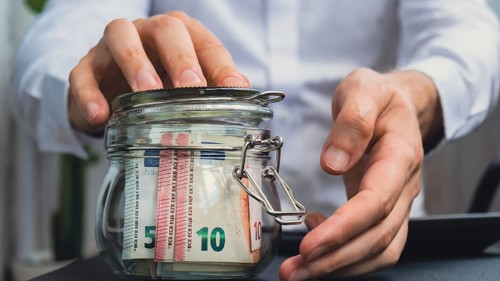 Euro Banknote Saving Money In Glass Jar. Unrecognizable man Moderate Consumption on calculator And