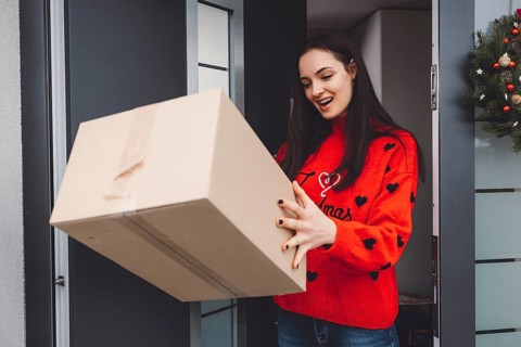 Cheerful young woman excited over a package she just received. Woman getting her christmas gift in