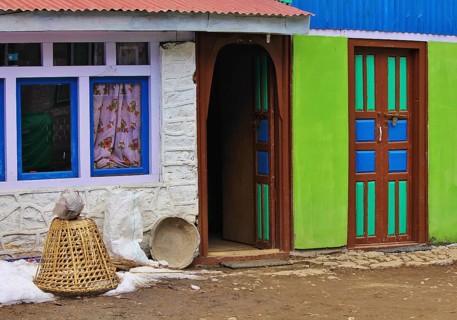 Colorful painted doors and facade. Braided basked used for transporting goods. Scene in Nepal