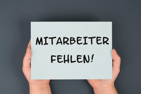 The words shortage of employees are standing in german language on the paper, skilled workers are