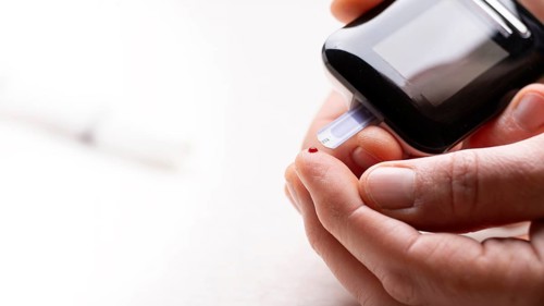 Pierced caucasian finger ready to measure glucose level by glucose meter closeup view with