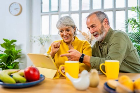 Happy caucasian senior couple shopping online using tablet at home