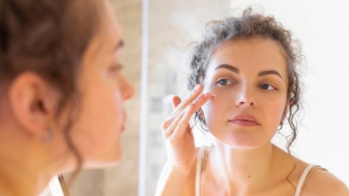 Woman looking mirror applying cream face