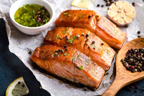 Delicious fried salmon fillet, seasonings on blue rustic concrete table. Cooked salmon steak with