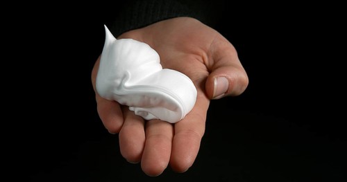 Hand of Woman and shaving foam against Black Background