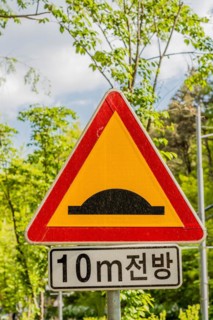 A traffic sign warning of a speed bump ahead with Korean text beneath, in Daejeon, South Korea,