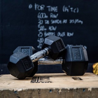 Closeup of two dumbbells on a wooden box in front of blackboard at the gym. Wod, workout of the day