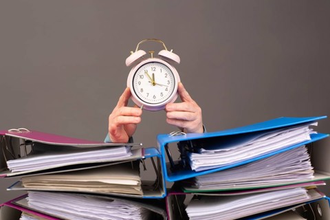 Alarm clock standing next to pile of file folders, burnout, stress and overworked, pressure at