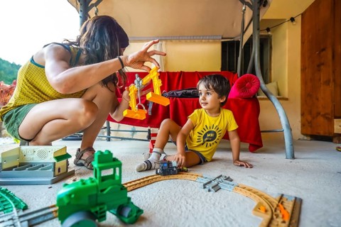 Mother and son enjoying quality time together, playing with a toy train and crane on a summer day