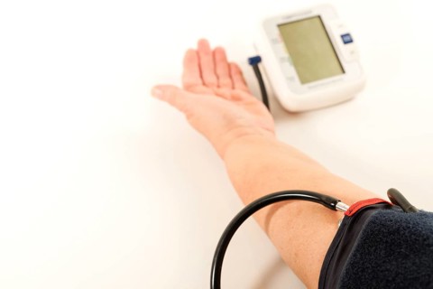 Woman's arm taking blood pressure on a white table with space for text
